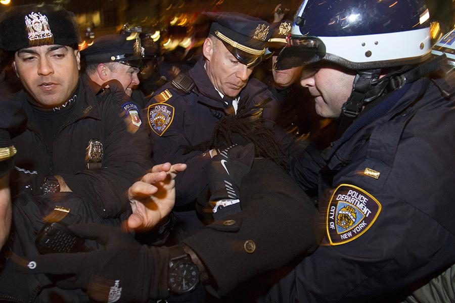 Four police officers restrain a protester. 