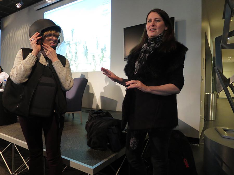 A volunteer from the audience tries on filmmaker Carol Cassidys bulletproof vest and flak helmet, two relics of working on conflict zones.