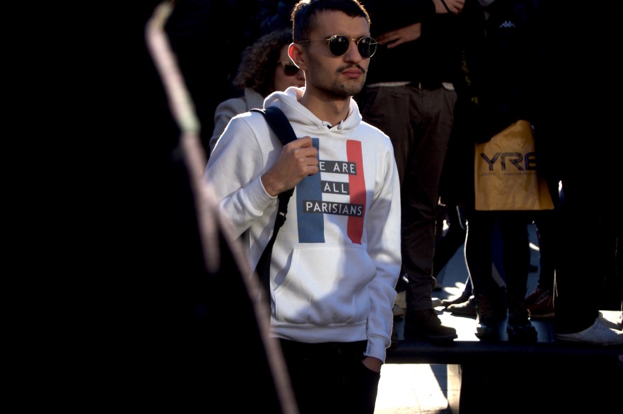 A young man watches on, wearing a sweatshirt to show his solidarity with the people of Paris.