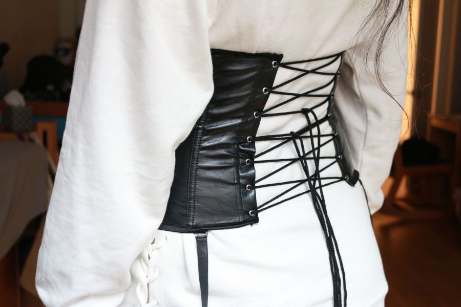 A lace-up faux-leather corset paired with a white hooded sweatshirt. Aspects of the traditional Victorian style corset have seen a revival recently, appearing on the runways of brands like Giambattista Valli.