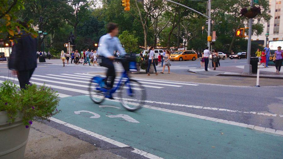 A cyclist bikes past on a Citi Bike. There are many Citi Bike locations on the NYU campus, as well as normal bicycle racks and NYU-specific racks.