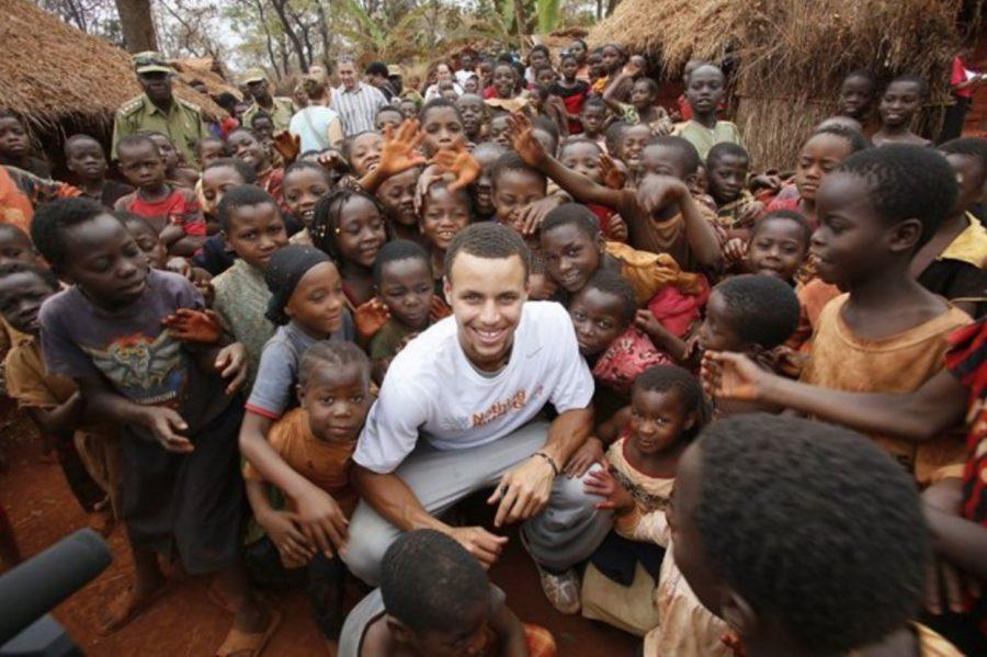 Golden State Warriors point guard Steph Curry with children at Nyarugusu Refugee Camp in Tanzania. Curry worked with Nothing But Nets, a charity that donates malaria-preventing nets to communities across Africa.