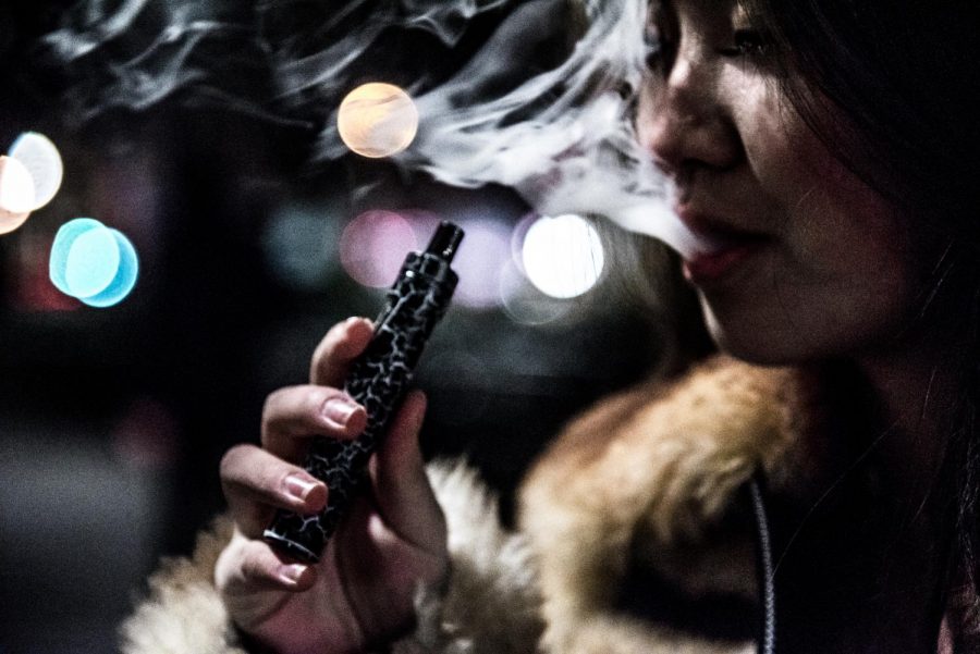A student vapes in Union Square at night. (Staff Photo by Sam Klein)