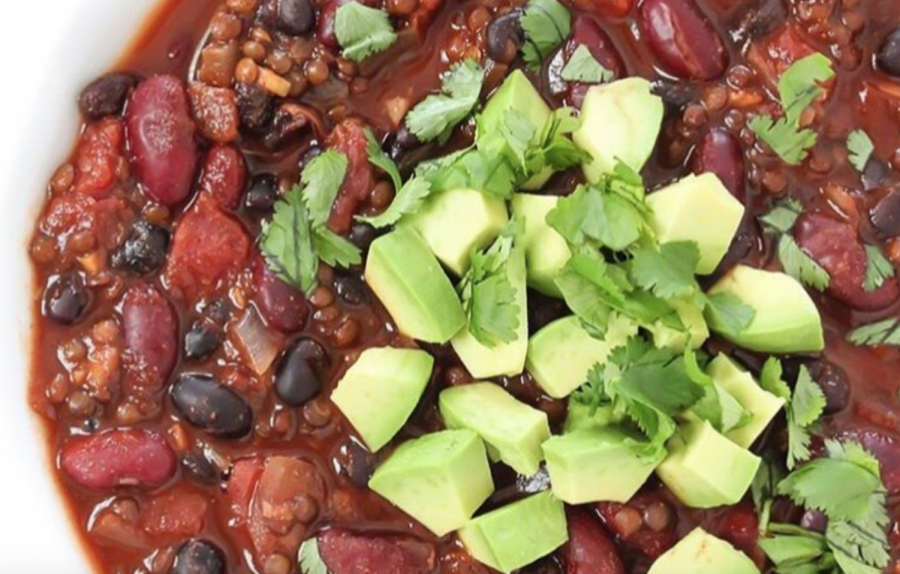 A bowl of lentil chili topped with diced avocado.