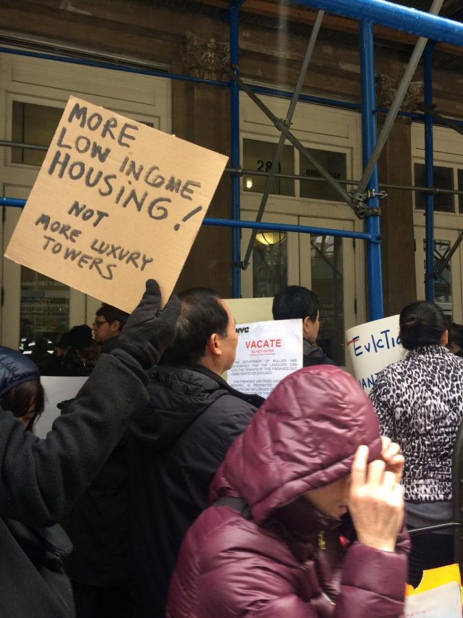 A demonstrator holds a sign calling for improved housing and criticizing luxury development.