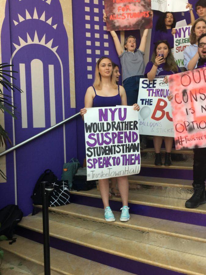 On the steps inside the Kimmel Center for University Life, a student activist holds a sign that reads, NYU would rather suspend students than speak to them #TrusteeTownHall.