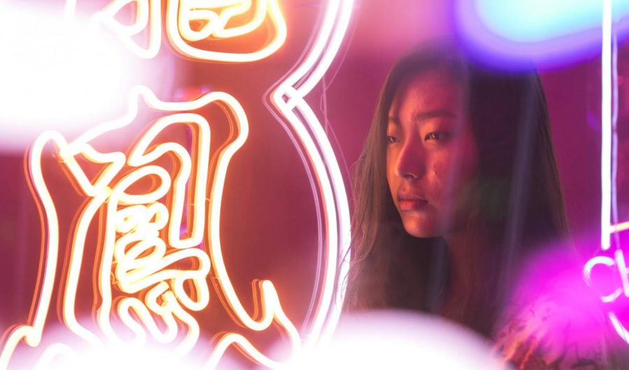 A visitor stands among the neon signs.