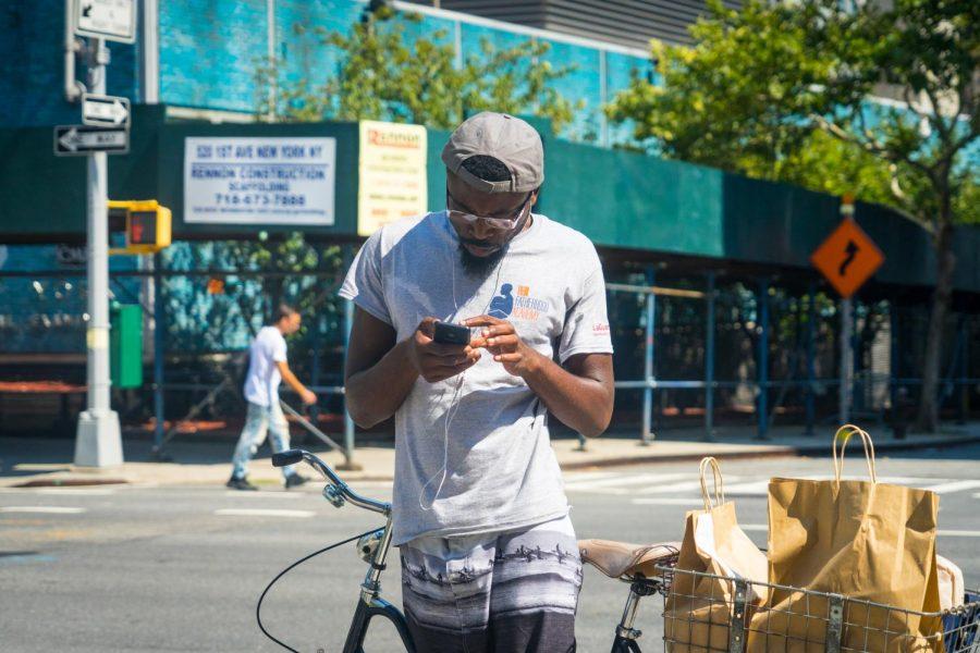 A man uses earbuds on a street corner.