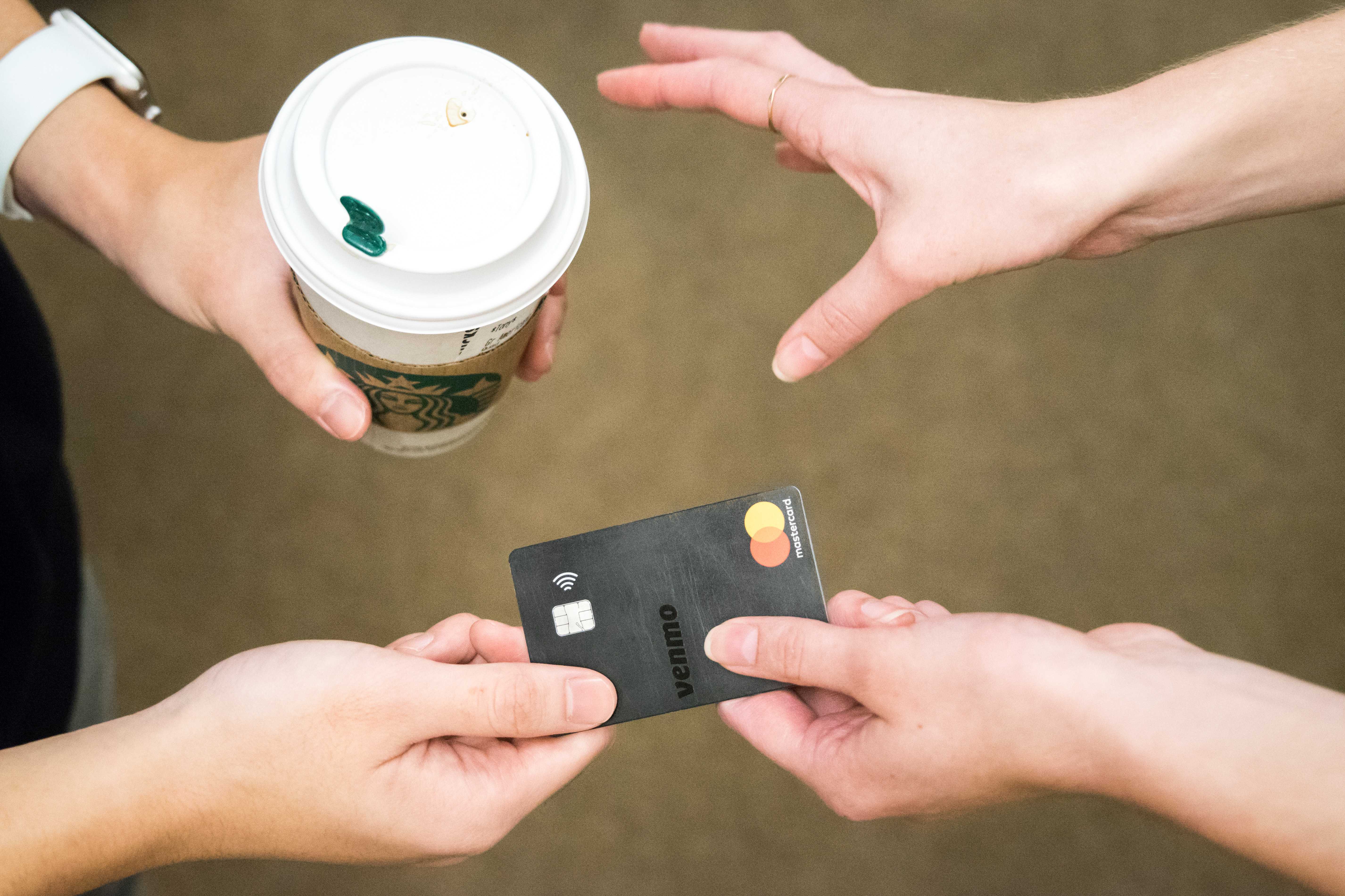 Two pairs of hands exchange a Venmo card for a cup of coffee. (Alana Beyer)
