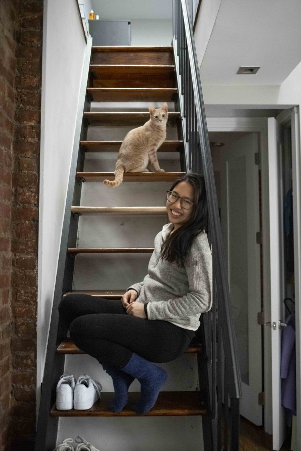 Jenny Du and her roommate’s cat sit on her East Village apartment’s staircase, which leads into her room. This past summer she footed her entire rent. (Photo by Katie Peurrung)