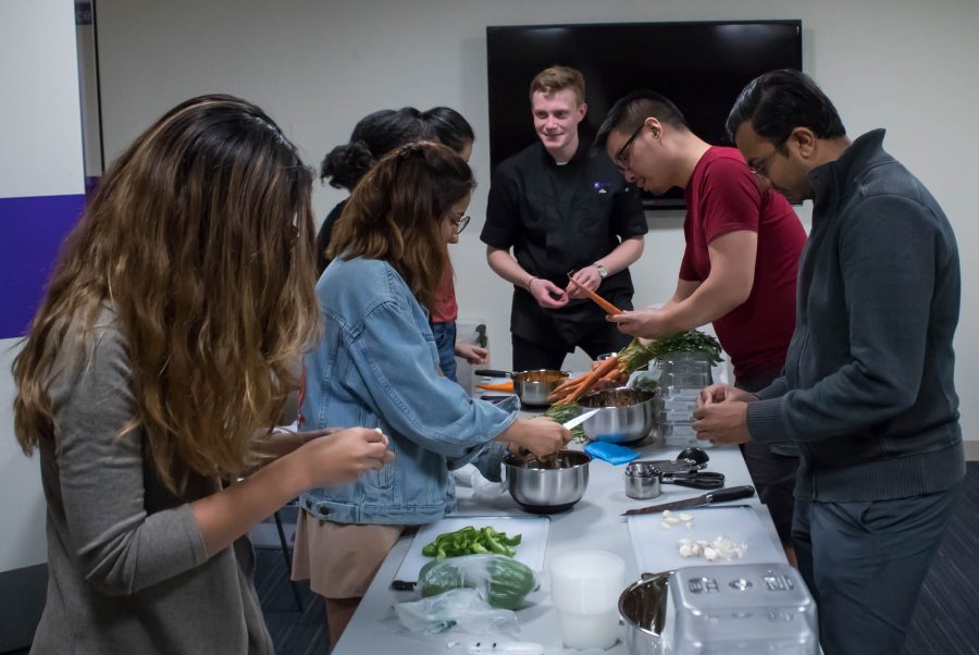 Steinhardt+first-year+Abe+Konick+%28center%29+teaches+a+group+of+students+how+to+cook+spaghetti+sauce+at+the+first+Open+Kitchen+event+of+the+semester.+%28Photo+by+Victor+Porcelli%29