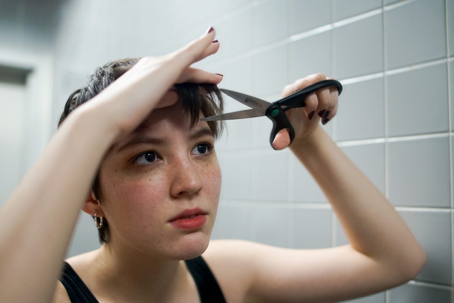 A student trims her bangs in front of a mirror. (Staff Photo by Min Ji Kim)