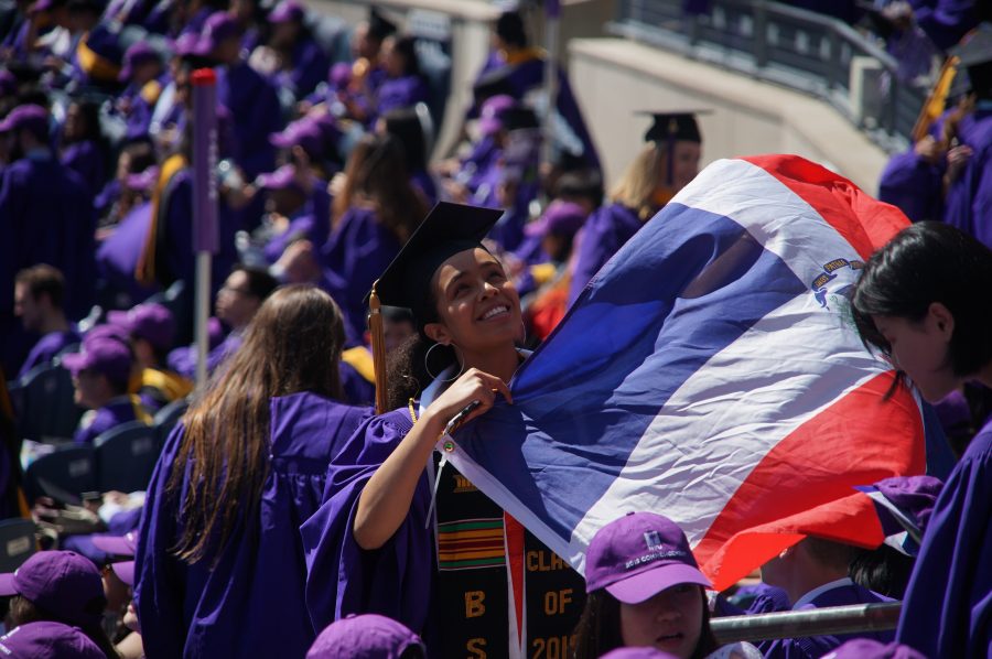 An NYU graduate holds up the Dominican Republic flag while in the stands at Yankee Stadium. The Class of 2020 commencement has been delayed due to the coronavirus pandemic. (Photo by Alana Beyer)