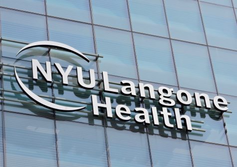 The glass exterior of the N.Y.U Langone Health building, with a broken circle around the word N.Y.U on the signage.