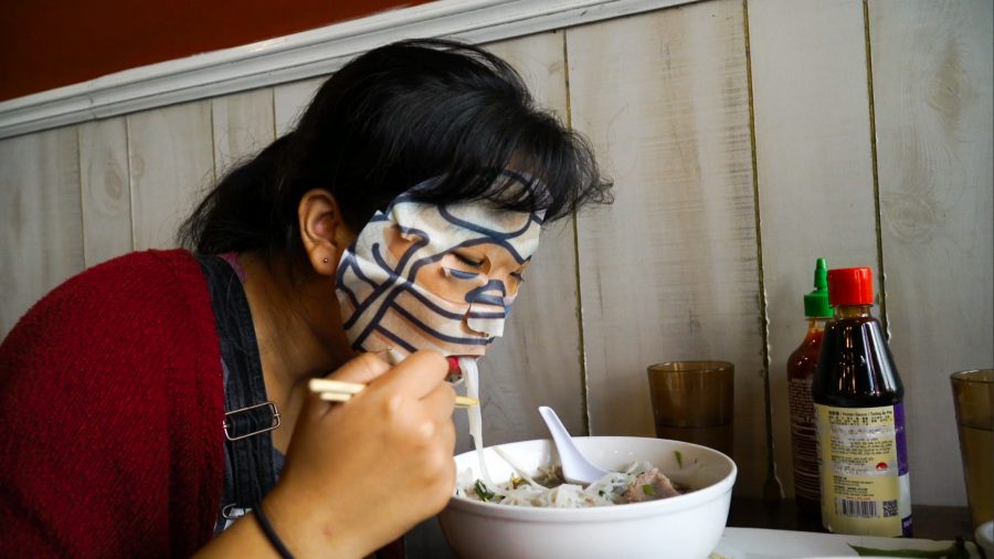 Marva Shi, our deputy multimedia editor, slurps up a bowl of pho in Saigon Shack while wearing a Gudetama pancakes facemask. (Staff Photo by Min Ji Kim)