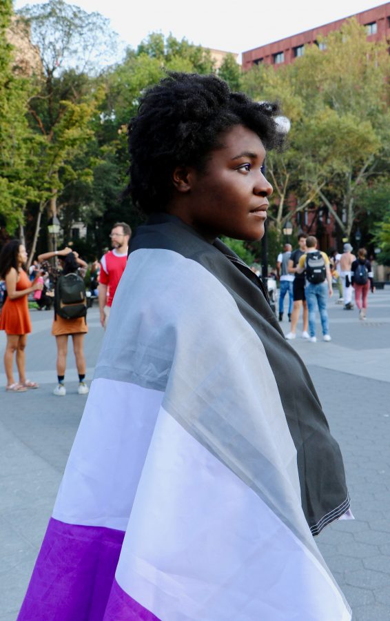 Tisch drama sophomore Journey Brown-Saintel stands in Washington Square Park with the asexual flag wrapped around her body. (Photo by Sara Miranda)