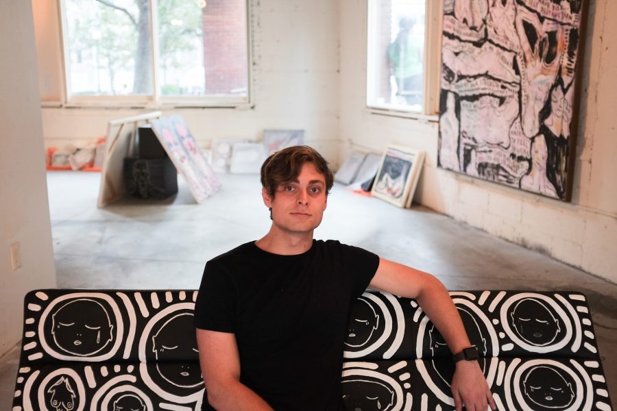 Tyler Cooperman sits on a custom painted Patrick Church couch in his exhibition at 117 Beekman. (Staff Photo by Claire Fishman)