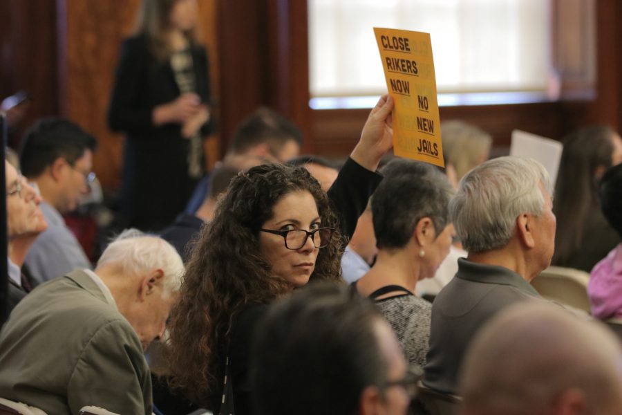 A woman holds a sign calling for the closure of the Rikers Island jail. (Photo by Sam Clegg)