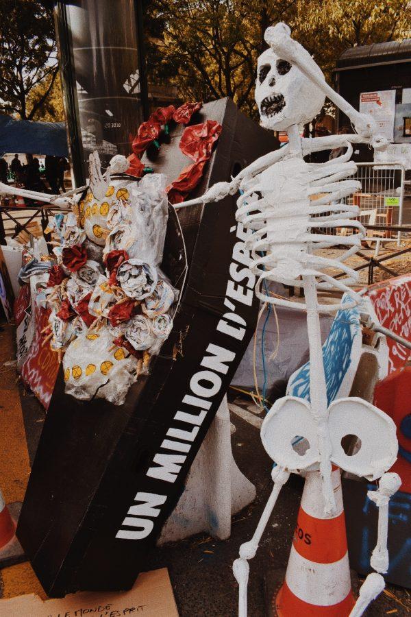 An artist's installation piece, comprised of a human skeleton model next to a coffin with a giant plastic wreath, symbolizes the dangers of plastic.