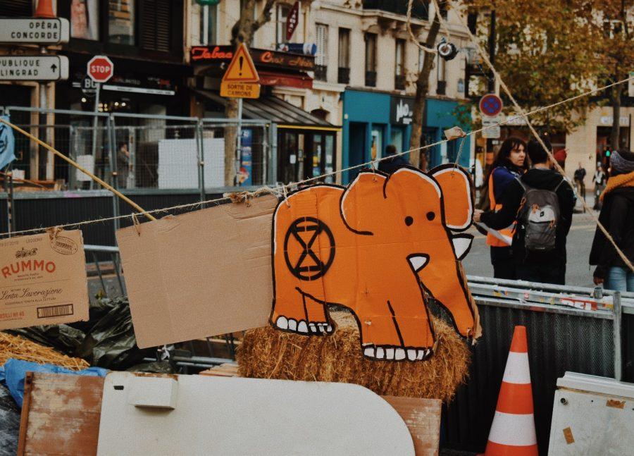Homemade signs of the Extinction Rebellion logo hang up in front of the street blockade.
