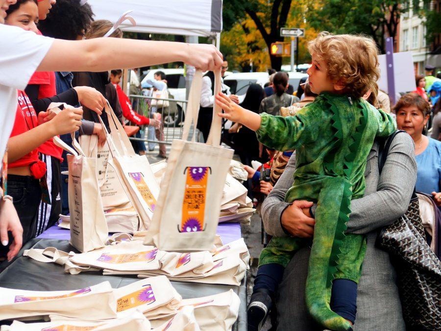Pictured is little boy dressed as a dinosaur receiving a free trick-or-treat bag. On Halloween Thursday, the annual Children’s Halloween Parade took Place at Washington Square Park (Staff Photo by Chelsea Li)
