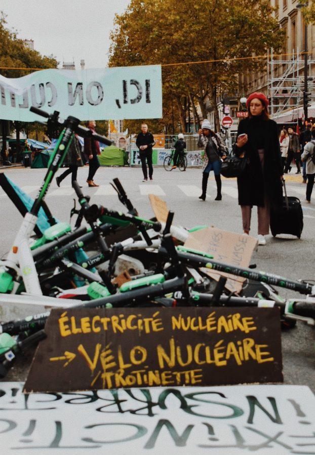 A passerby stops to read the art installation piece against the electric scooters popular throughout the city.