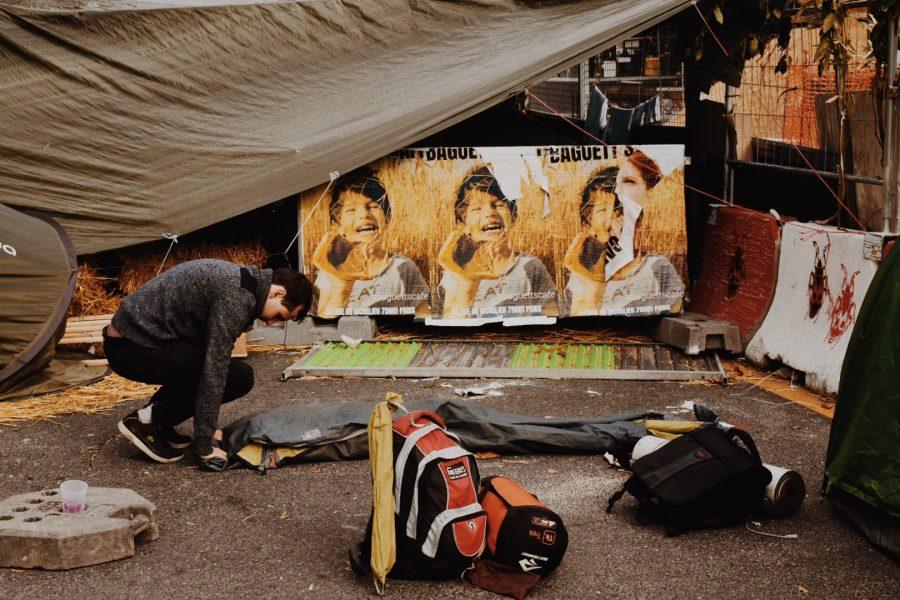 A protester takes down his tent, surrounded by colorful posters and his gear.