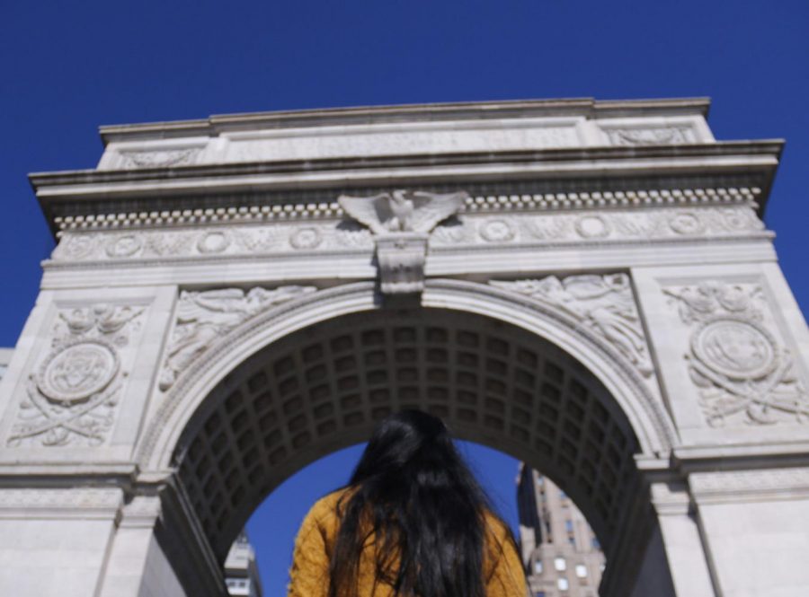A student looks up at the Washington Square Park arch, a hallmark of NYU's campus. An email sent out by Provost Katherine Fleming announced that NYU plans to return to campus in the fall. (Staff photo by Alex Tran)
