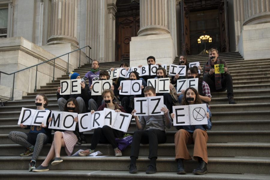 An activist group named Extinction Rebellion covered their mouths with black duct-tape and protested outside City Hall Monday morning. They handed out flyers urging climate change action, holding up notebooks with letters that make up “Decarbonize, Democratize, Decolonize.” (Photo by Andrew Califf)