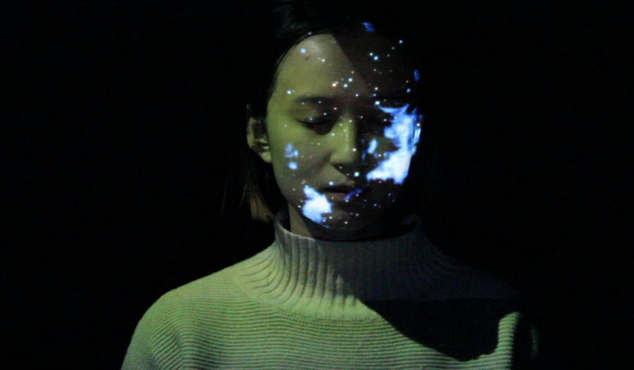 Huiyi Chen projects images of cells and the universe onto her face during her performance piece “Fast-forward Life.” (Photo courtesy of Huiyi Chen)