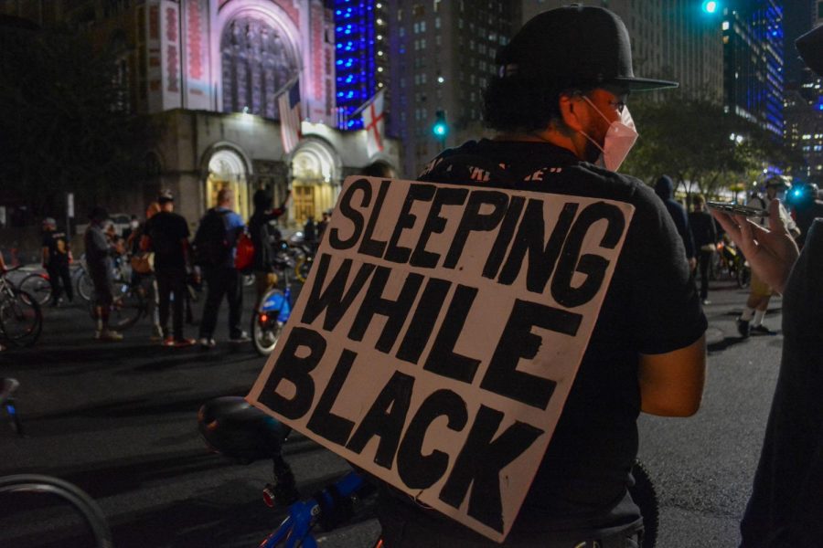 A protester hangs a sign on their back reading "Sleeping While Black" in reference to Breonna Taylor's murder at the hands of Louisville cops. Taylor was sleeping when officers broke into her house and killed her. (Staff Photo by Manasa Gudavalli)