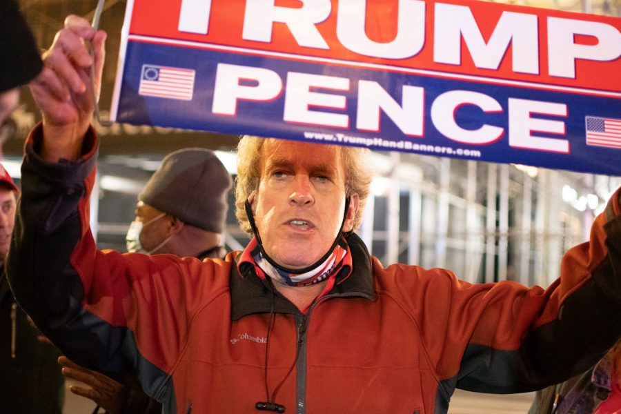 A Trump supporter holds a Trump Pence poster at a rally in midtown on election night 2020. Trump left a legacy in the Republican Party. (Staff Photo by Jake Capriotti)