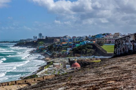 Waves crashing onto the shore with a view of the Puerto Rican coast in the city of San Juan during a sunny day with blue skies.