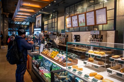 Astor Place Starbucks employees prepare orders as customers wait in front of the counter inside the cafe.