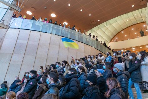 Students are seated on the lobby steps of the Kimmel Center for University Life, with one student waving a Ukrainian flag above the crowd.