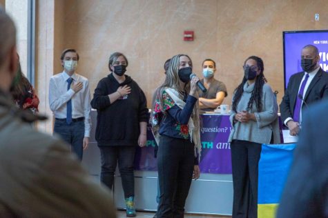 A crowd of NYU and Ukrainian community members is gathered in the entrance lobby of the Kimmel Center for University Life listening to a singer perform the Ukrainian National Anthem at NYU's Vigil for Ukraine.