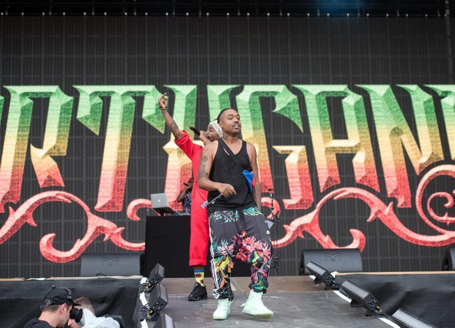 Hiphop duo EARTHGANG (Olu and WowGr8) perform on stage. Behind them, an EARTHGANG logo is projected on-screen. The logo is an gradient of the Rastafari flag fading from green to yellow to red.