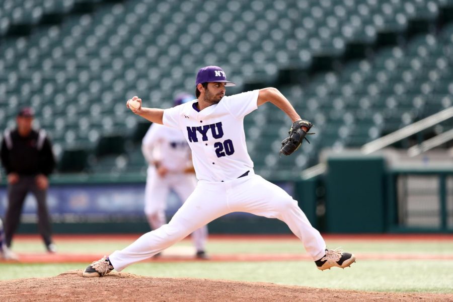 A student baseball player wearing a white uniform with the NYU logo and number 20 is throwing a baseball. The stadium has green seats and brown dirt on the field.