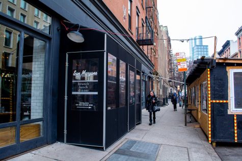 The facade and entrance to San Marzano. Outside the building is a temporary black winter vestibule with the restaurant's name printed on the door.