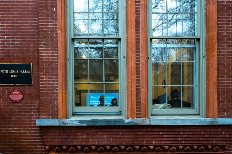 Two windows surrounded by brick. Through the windows, a college class is being taught.