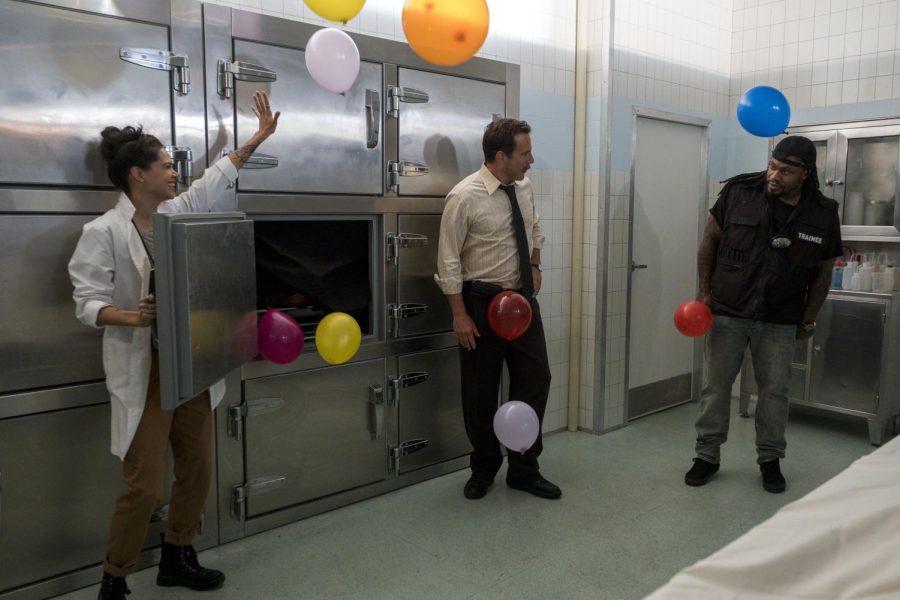 Left to right: Lilan Bowden, Will Arnett and Marshawn Lynch in a morgue with colorful balloons flying out of one of the cabinets.