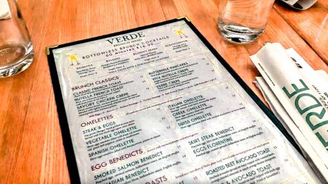 A menu for Verde on Smith on top of a wood table. Next to the menu are two glasses filled with water.