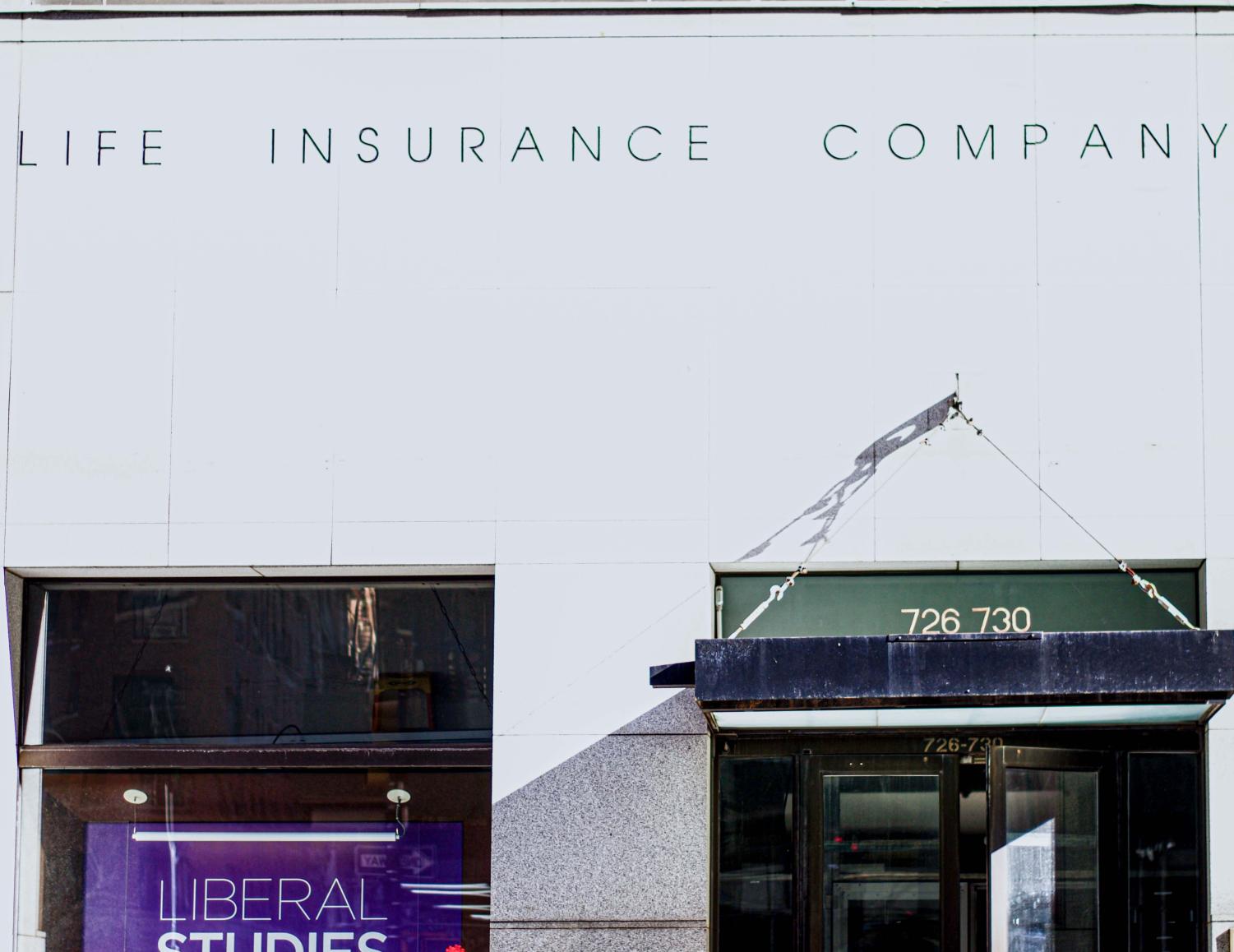 The gray stone facade of 726 Broadway with a green awning hanging above the entrance. Toward the top of the building, the text “Life Insurance Company” is etched into the stone.