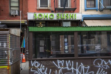 The facade and outdoor dining structure of Soho Sushi. Above the structure and entrance, the restaurant's neon green sign is visible.