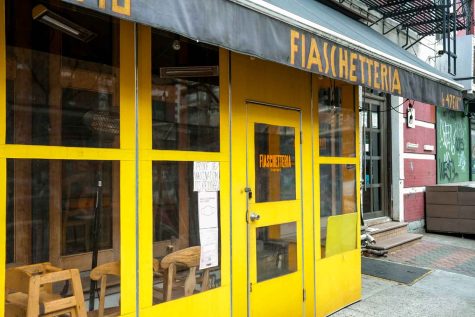 The all-yellow facade of Fiaschetteria “Pistoia.” Above the entrance is a black awning with the location’s name printed on it in the same yellow as the building.