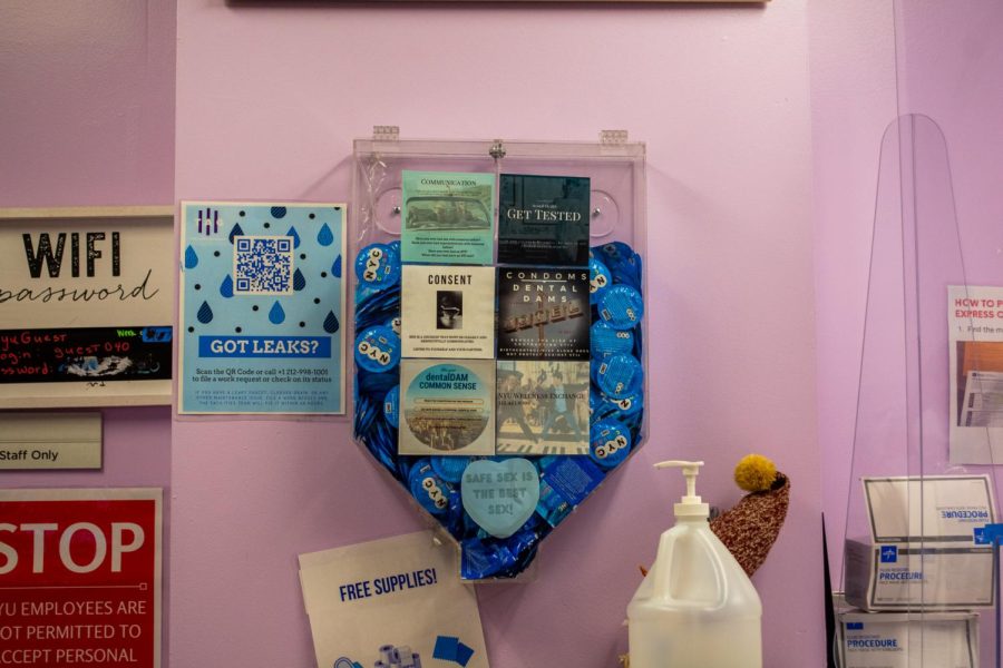 A filled transparent condom dispenser against a pink wall located in the resource center of the Third North residence hall.