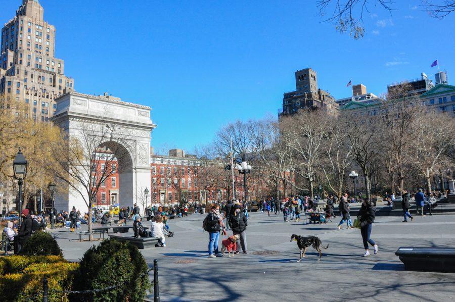 A scattered crowd of New Yorkers in Washington Square Park with the arch and fountain in view.