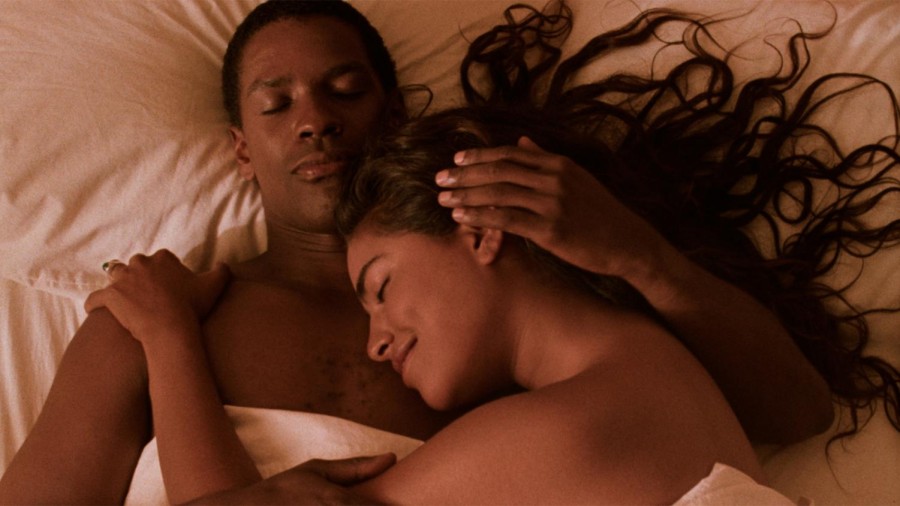 Demetrius Williams (Denzel Washington) and Mina (Sarita Choudhury) cuddling, naked, in a white bed.