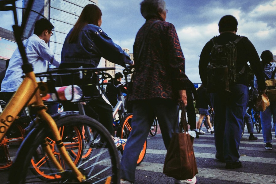 A crowd of people and cyclists walking across an intersection.