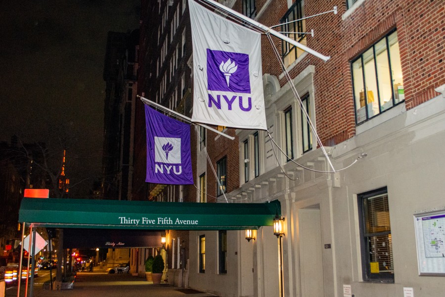 The facade of Rubin Hall with a dark green awning printed with the address “35 Fifth Avenue.” The awning is accompanied by two NYU banner flags on each side.